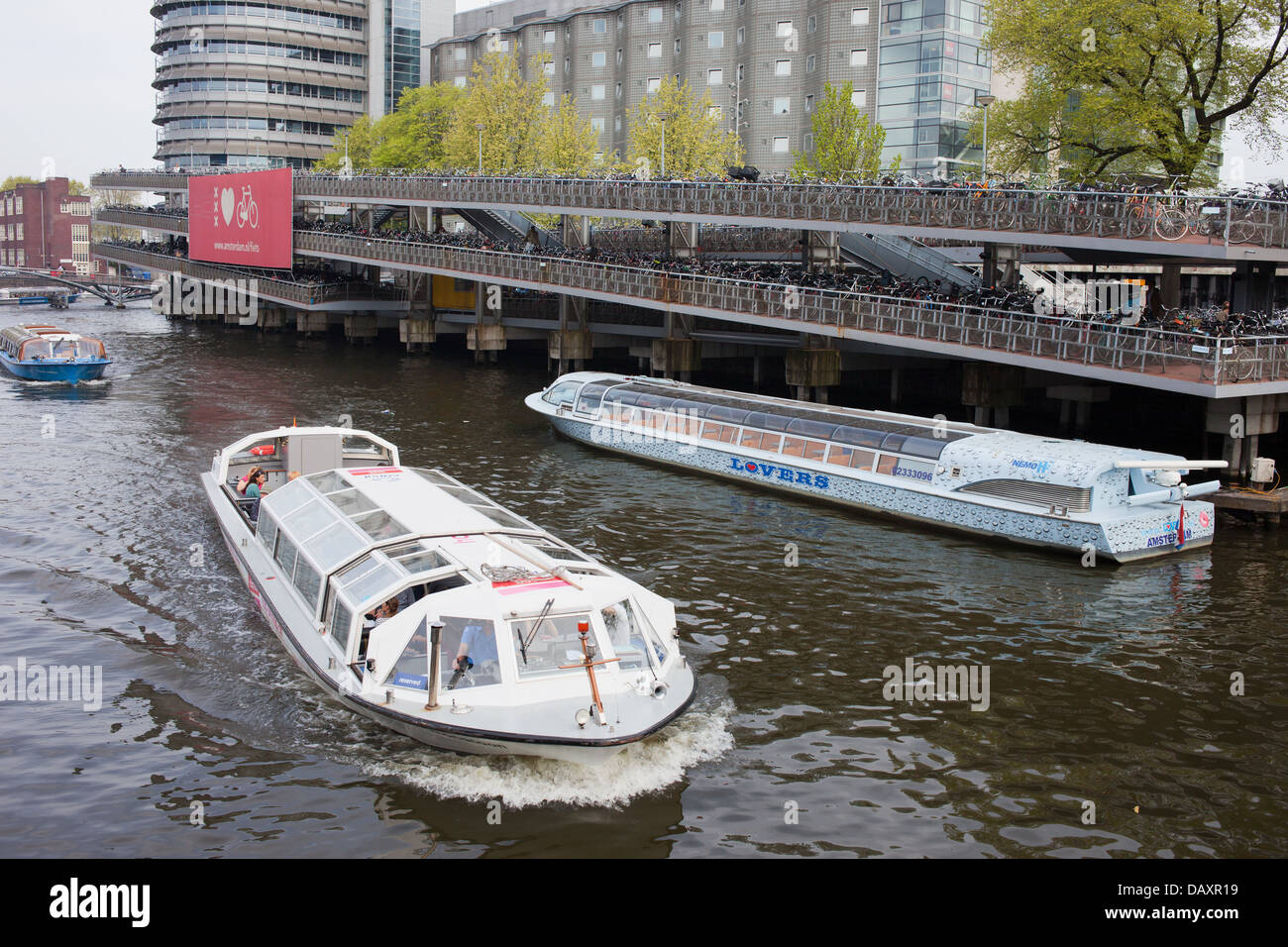 Boote auf Touren und große mehrstufige Fahrrad-Parken in Amsterdam, Niederlande, neben dem Hauptbahnhof. Stockfoto
