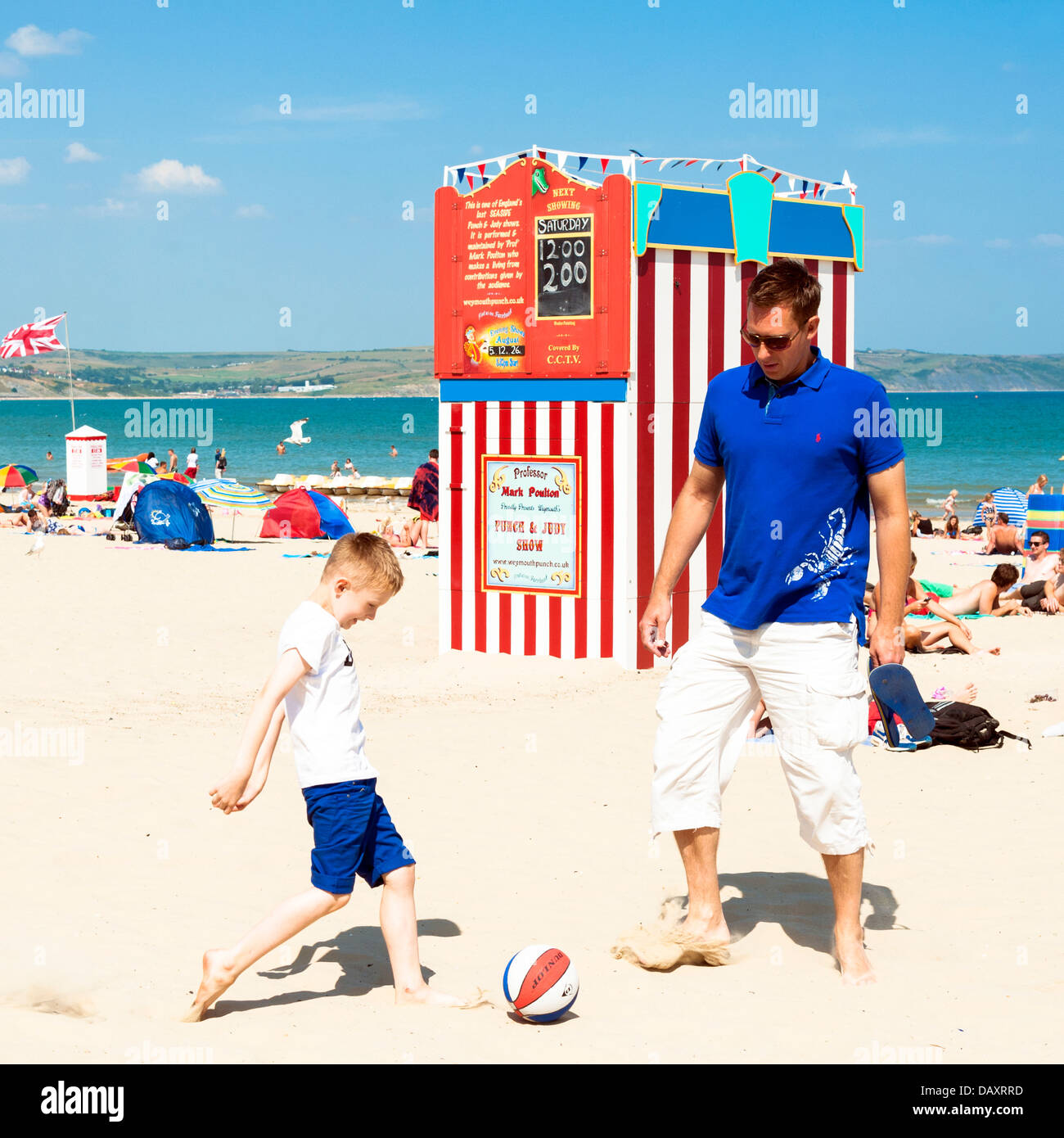 Mann & junge Spiel des Fußballs am Strand von Weymouth, Dorset, UK. Stockfoto