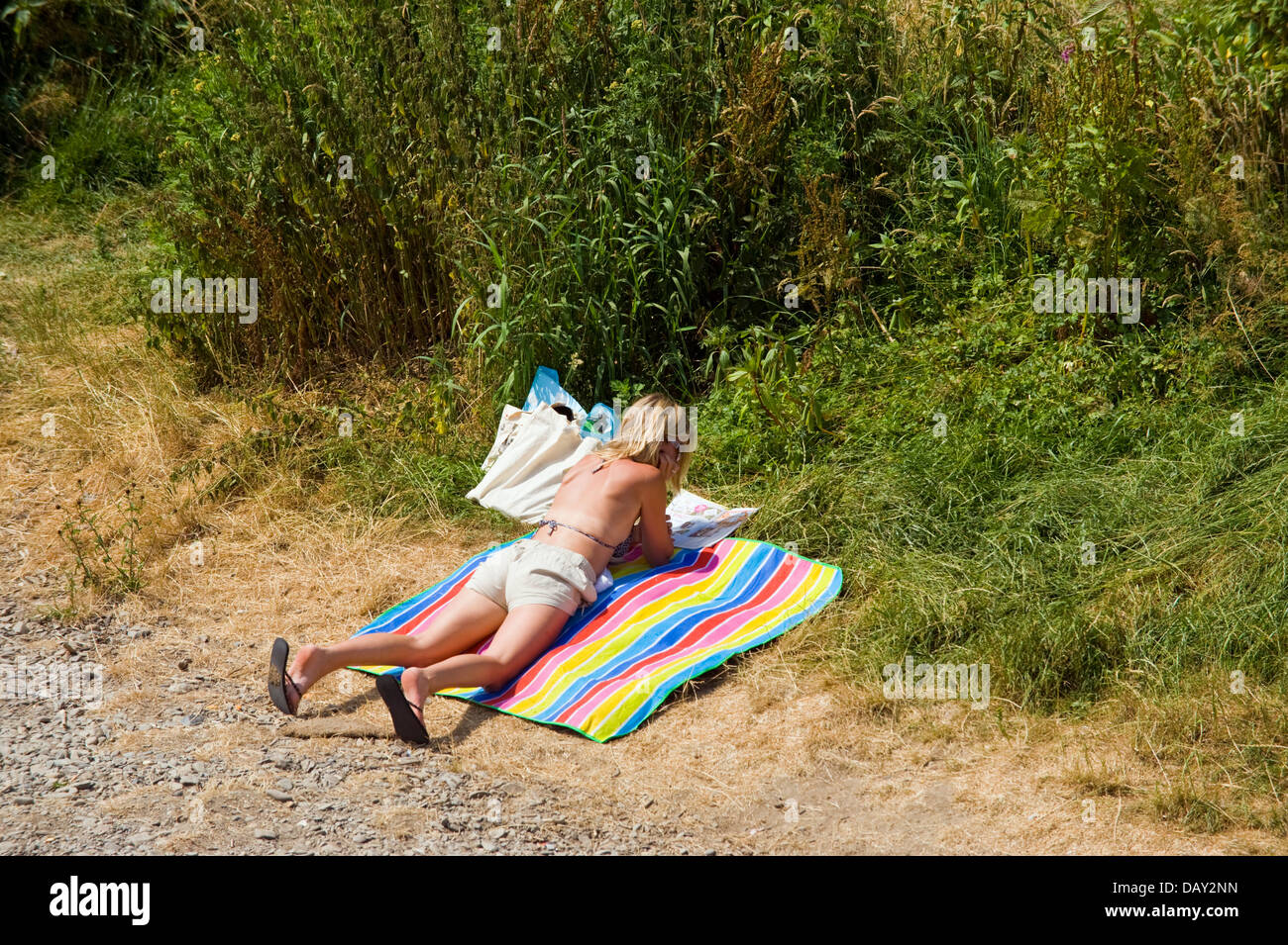 Frau liegend auf buntes Handtuch am Ufer des Flusses Wye bei Glasbury Powys Wales UK Sonnenbaden Stockfoto