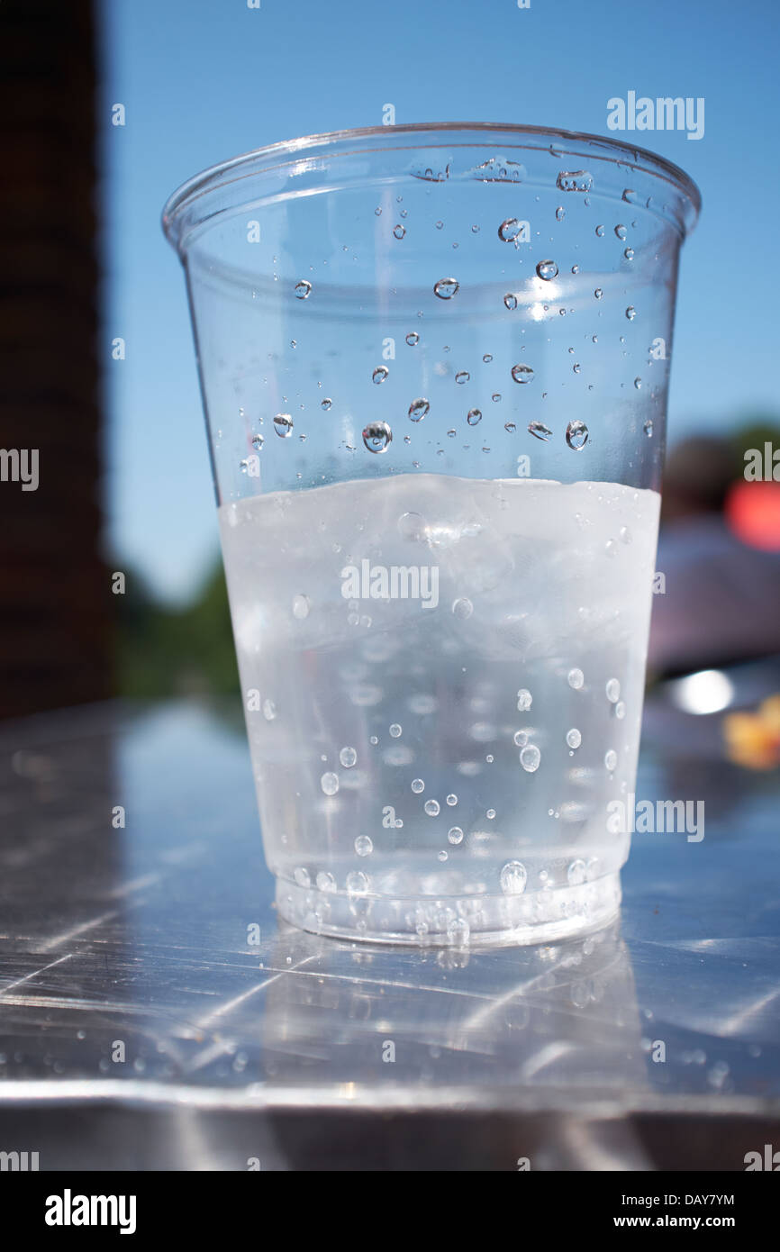 Eine halb volle Tasse kohlensäurehaltige Quellwasser auf ein Sommer Tag Weitwinkel schließen gegen einen sonnigen blauen Sommerhimmel Stockfoto