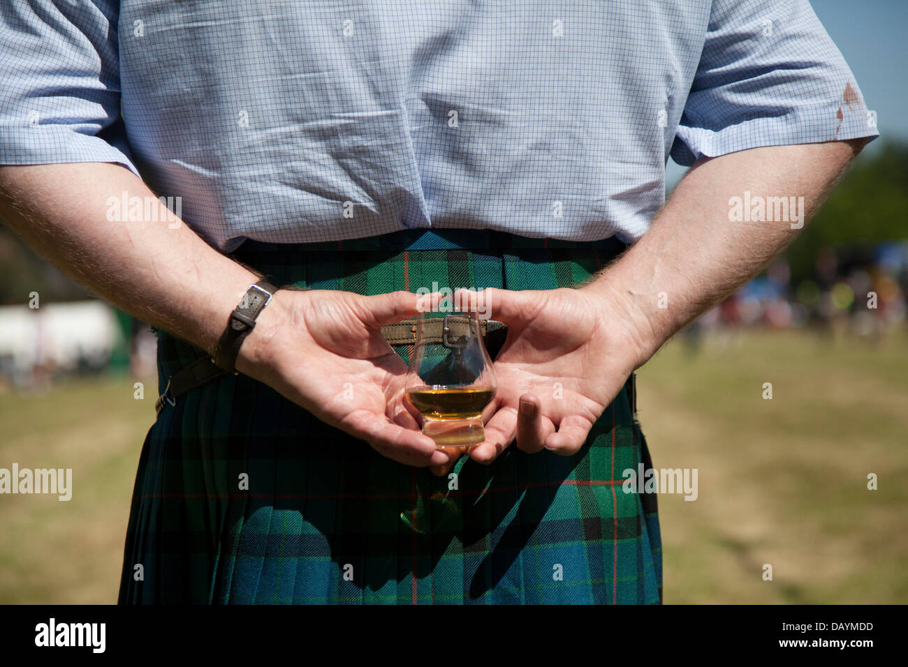 Man Glas Scotch Whisky in Tomintoul, Schottland, Großbritannien. 20. Juli 2013. Die jährlichen Spiele und Zusammenkünfte der Tomintoul Highland finden am 3. Samstag im Juli auf dem Ausstellungsgelände im Dorf statt. Dieses sportliche, historische und traditionelle schottische Ereignis in den vergangenen Jahren wurde von schlechtem Wetter heimgesucht und mehrmals abgesagt. Stockfoto