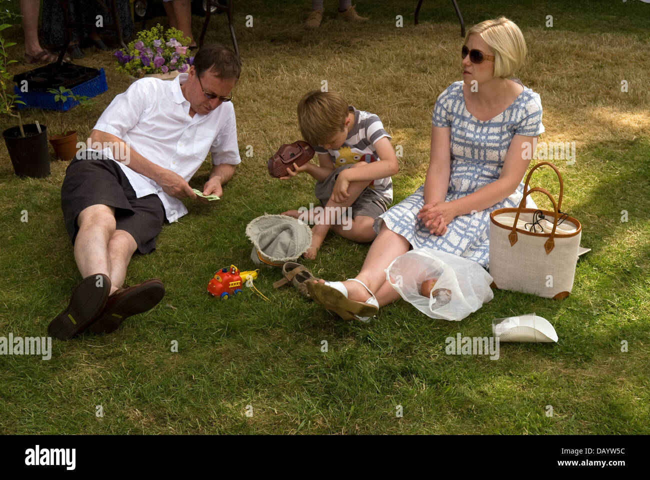 Familie entspannend auf Rasen am Worldham Dorffest, Hampshire, UK. Sonntag, 14. Juli 2013. Stockfoto