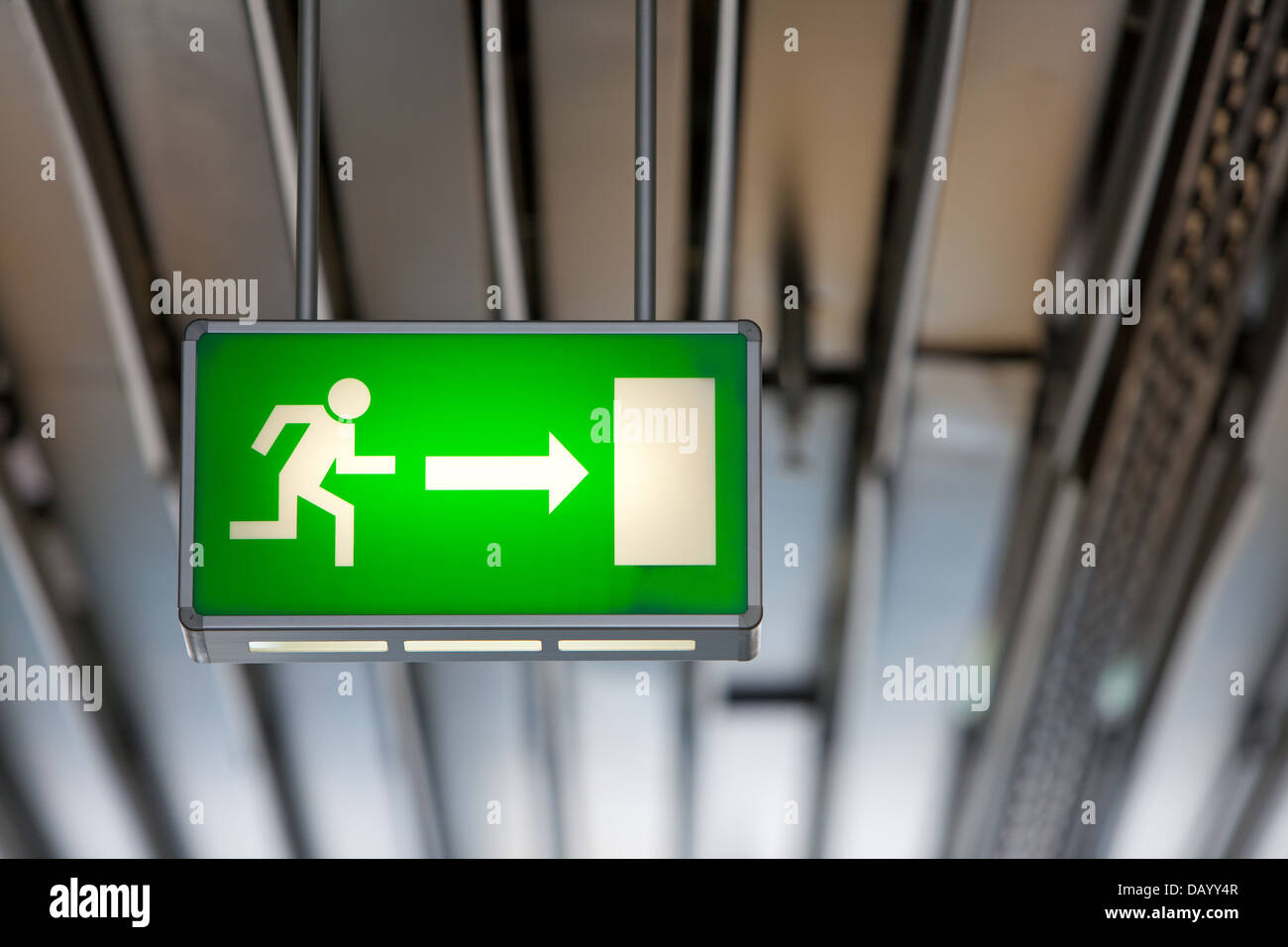 Beleuchtete grüne Notausgang Schild von der Decke abgehängt. Zeichen besteht aus einer laufenden Figur Stockfoto