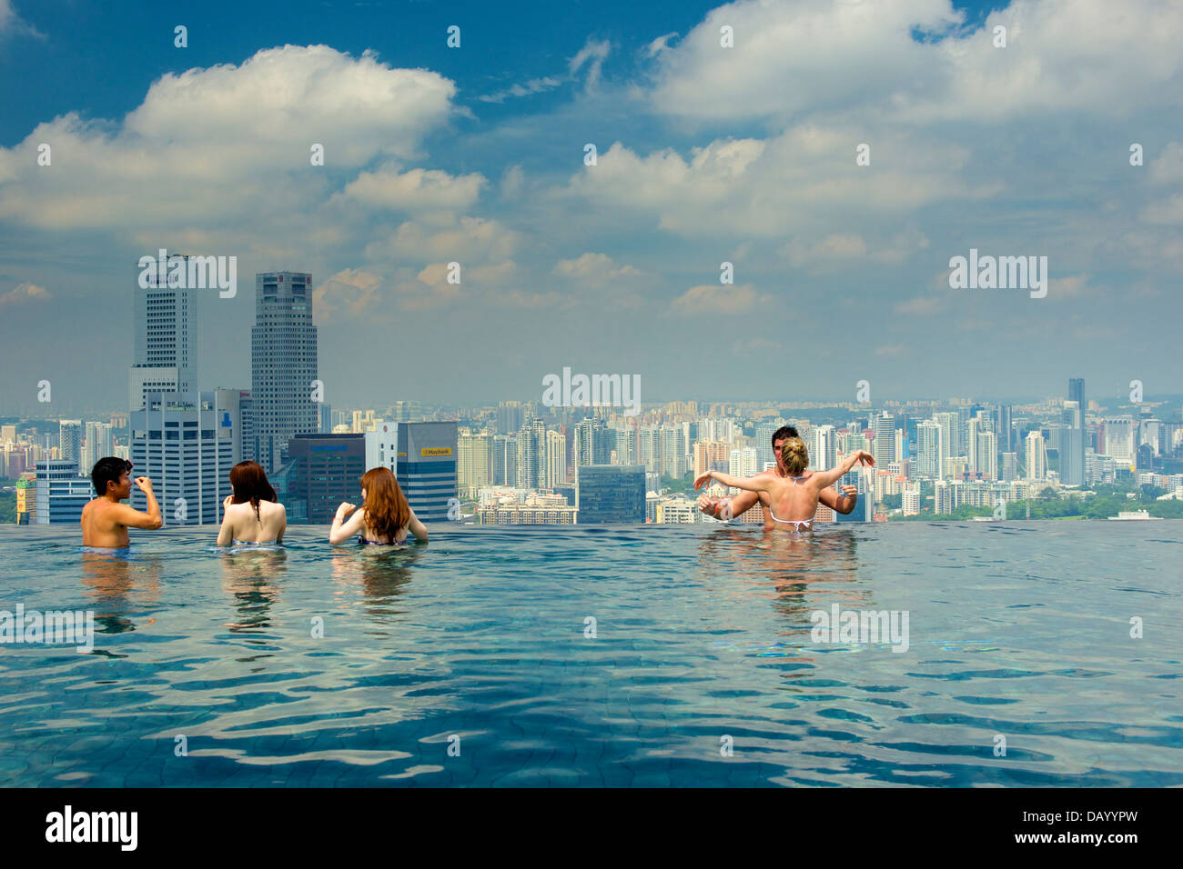 Gäste des Marina Bay Sands genießen ein Bad im Infinity-Pool des Hotels auf dem Dach und an die Sehenswürdigkeiten Singapurs Skyline Stockfoto