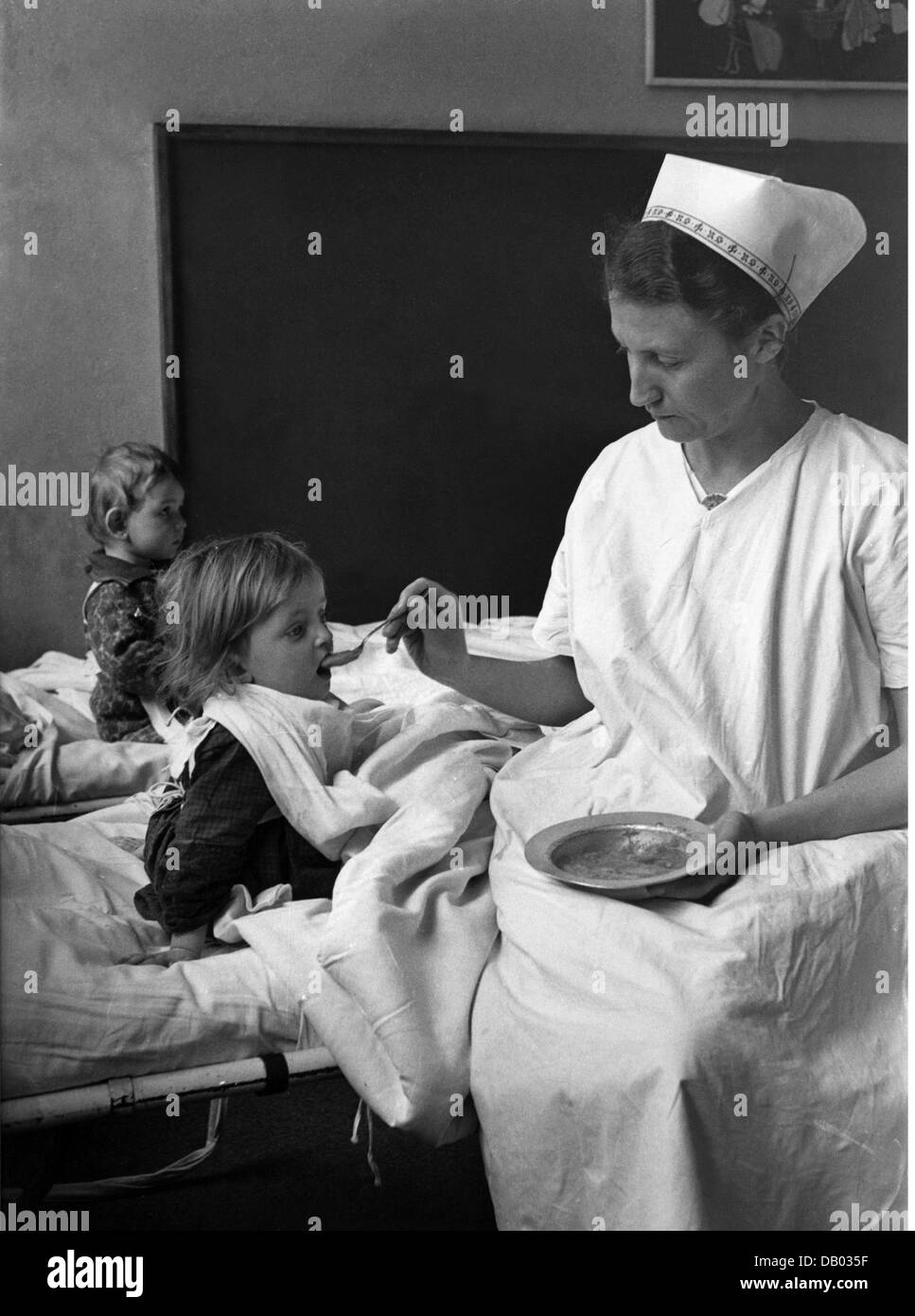 Nationalsozialismus, Organisationen, nationalsozialistische Volkswohlfahrt, NSV, NSV-Krankenschwestern, die ein Kind füttern, Ende der 1930er Jahre, Zusatzrechte-Clearences-nicht vorhanden Stockfoto