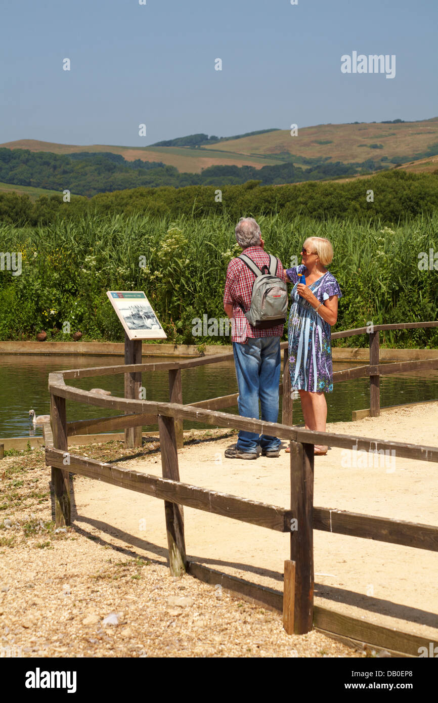 Frau, die Sonnencreme im Gesicht des Menschen beim Besuch Abbotsbury Swannery, Dorset UK an einem heißen sonnigen Tag im Juli Stockfoto