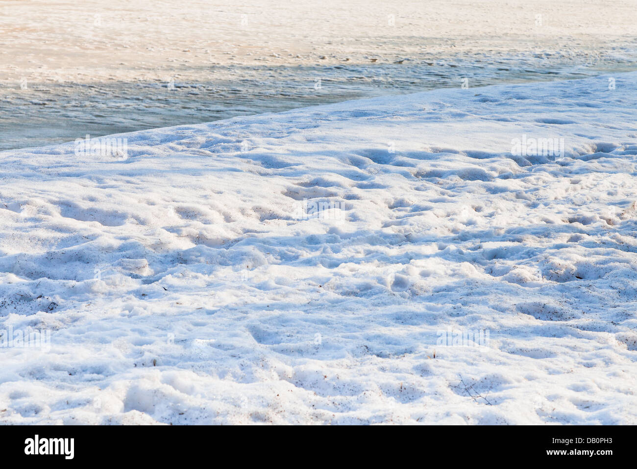 verschneiten Ufer des zugefrorenen Fluss im Frühlingsmorgen Stockfoto