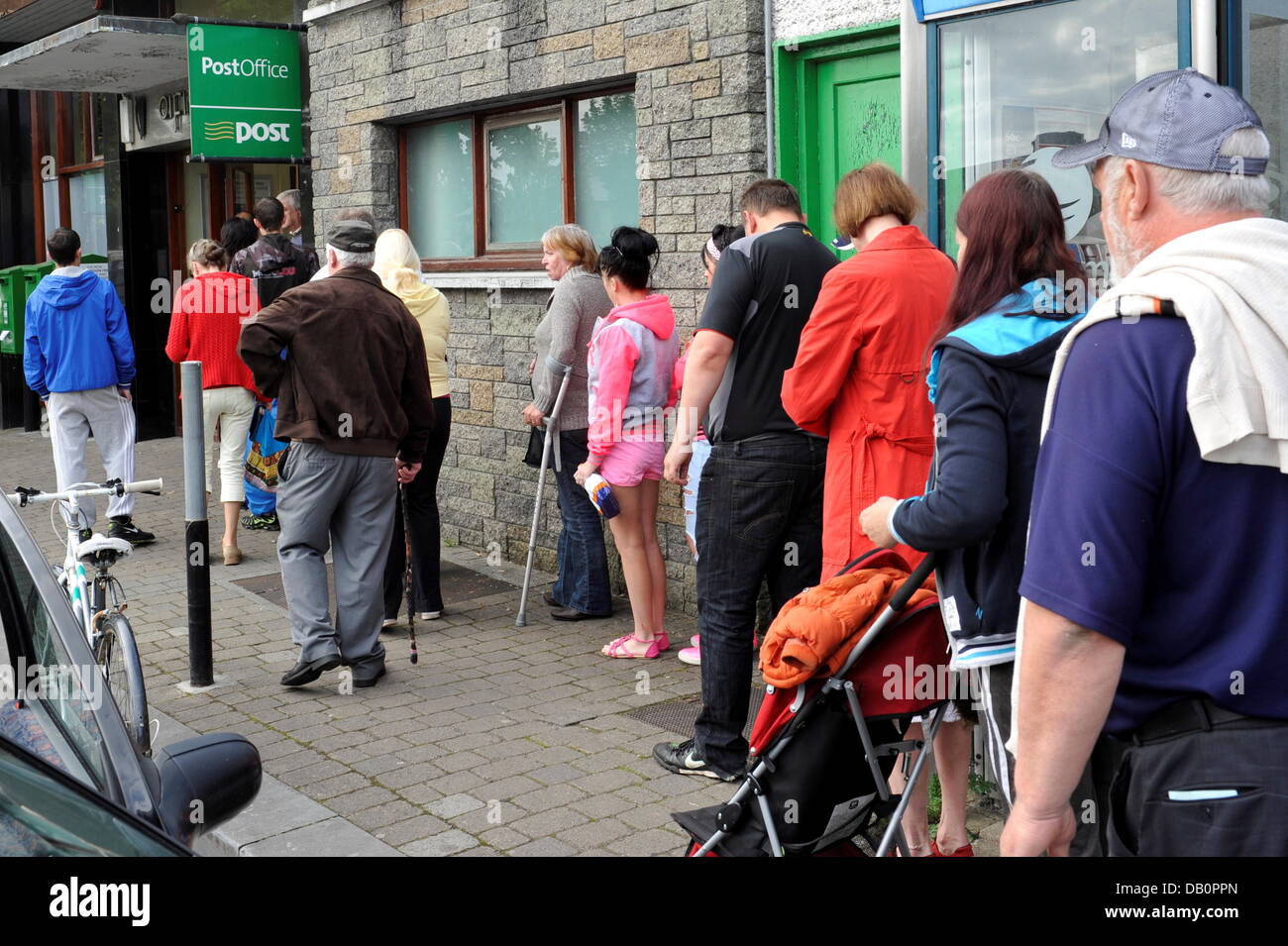 Sozialhilfeempfänger stehen in einer Warteschlange vor einer Postbank Niederlassung in Ballinasloe (Grafschaft Galway) auf Juni, 26.06.2013. Stockfoto