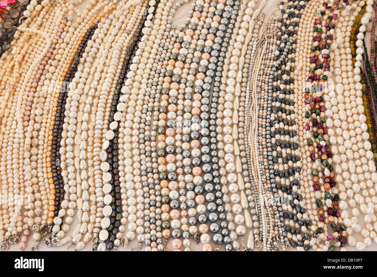 Saiten von Perlen und Perlenketten auf einem Marktstand in Italien, von Punjab, Indien - dezente Pastellfarben bezogen Stockfoto