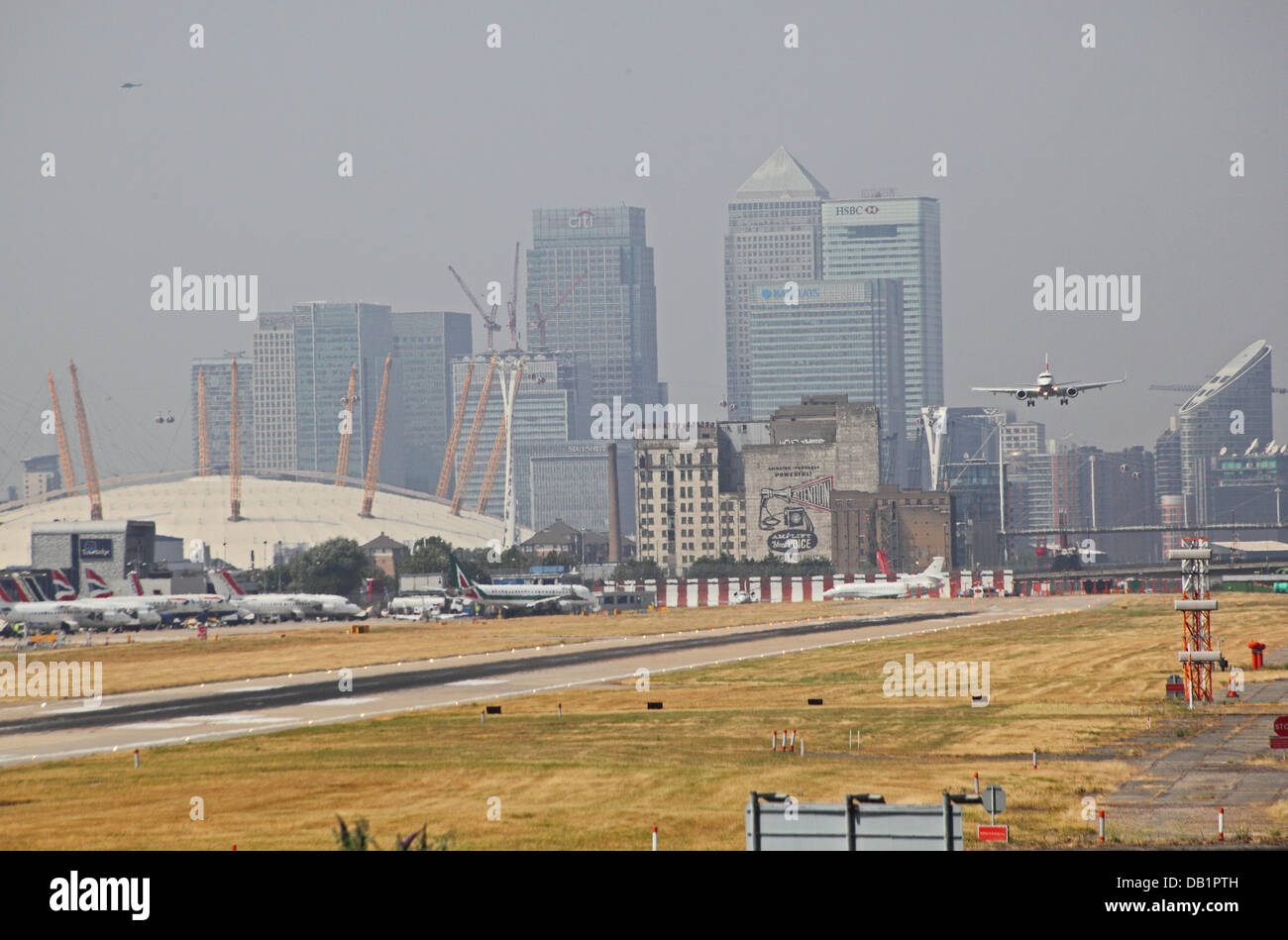 British Airways-Passagier-Jet landet auf dem Flughafen London City. Canary Wharf und den Millennium Dome im Hintergrund Stockfoto