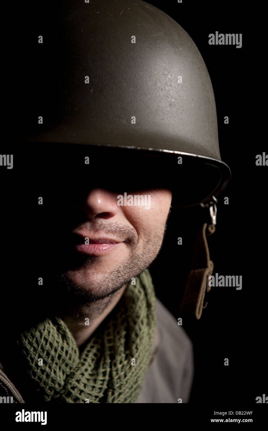 Porträt eines lächelnden Weltkrieg zwei US Soldaten, mit der Hälfte seines Gesichts im Schatten, vor einem schwarzen Hintergrund. Stockfoto