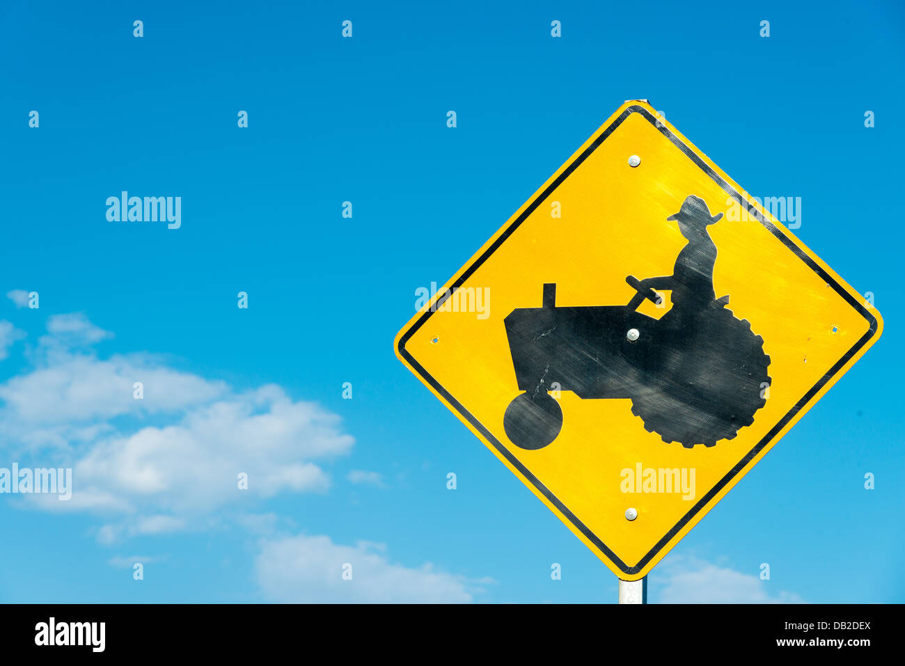 Eine gelbe Traktor überqueren Schild mit einem himmelblauen Hintergrund Stockfoto