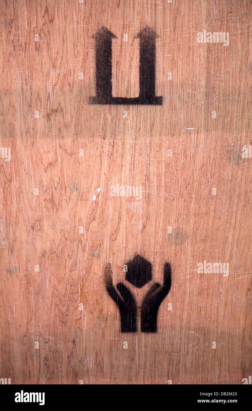 Pfeile und Hand With Care Symbole auf Holzkiste Stockfoto