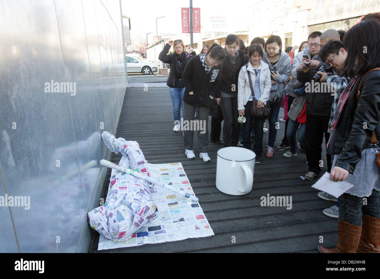 Kunst von betteln A "menschliche klassifiziert Zeitungsabteilung" Performance-Künstlerin in Peking, China, bat immer mehr neugierige Passanten und der Sammlung großen Menge Bargeld in seinem riesigen, überdimensionalen Tasse setzen. China - 29.03.2011 Stockfoto