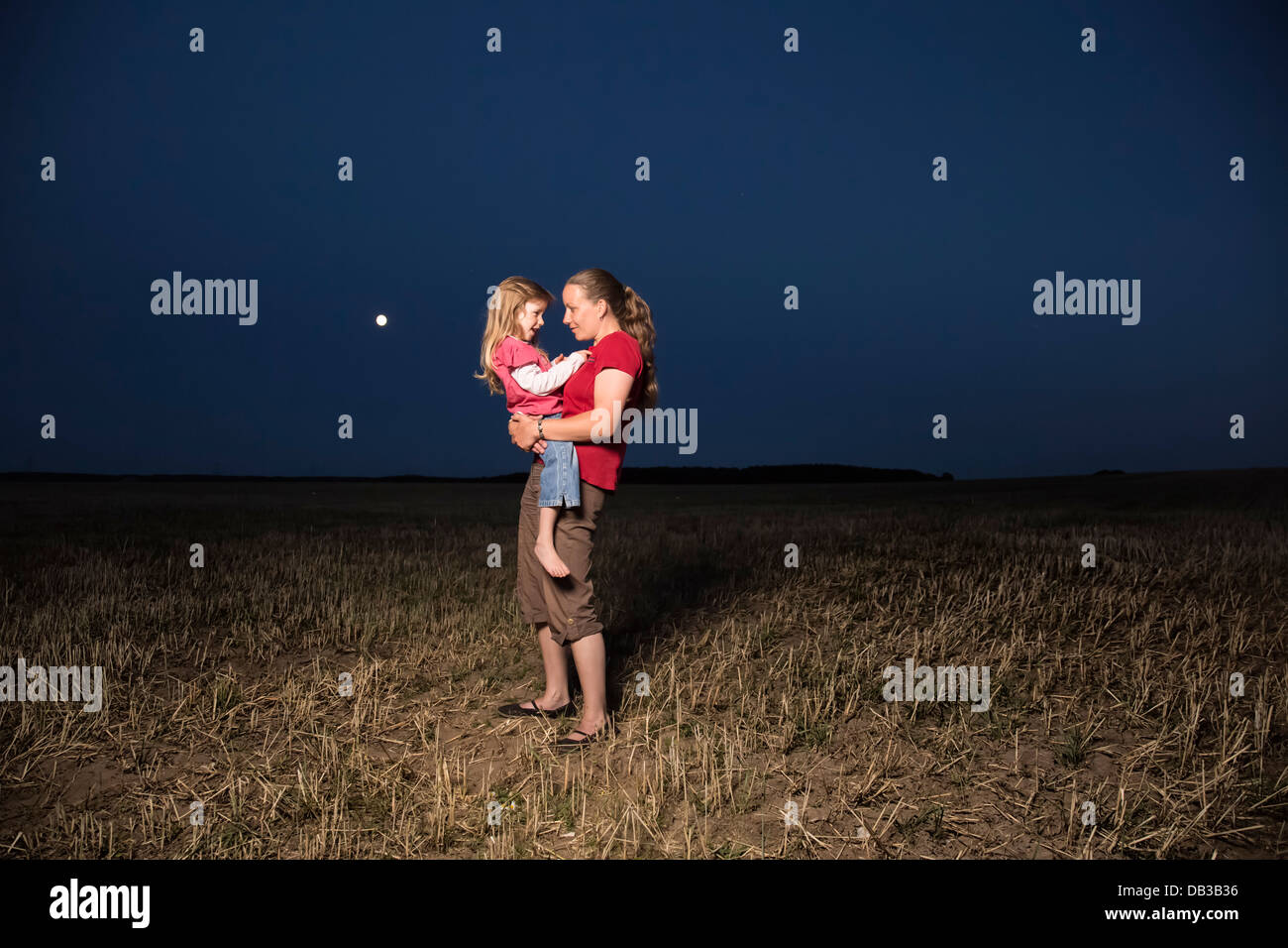 Mutter mit ihrer Tochter in der Nacht auf einem stubblefield Stockfoto