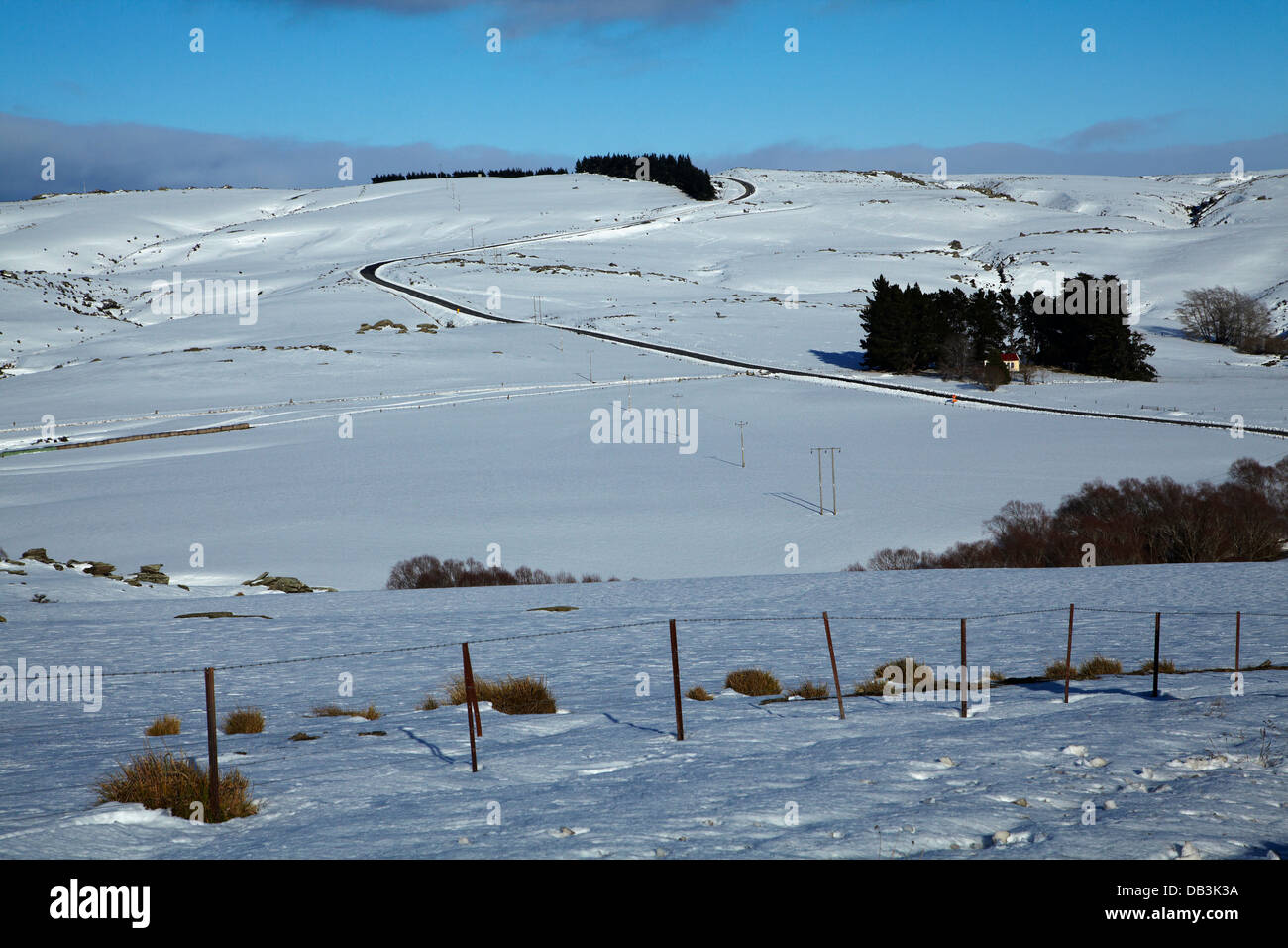 Verschneite Ackerland und State Highway 87 (Dunedin - Middlemarch Road), Strath Taieri, Otago, Südinsel, Neuseeland Stockfoto