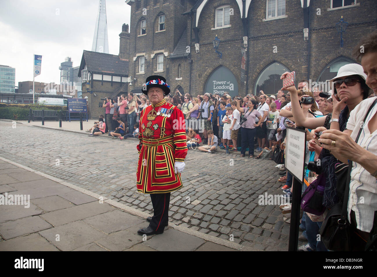 London, UK. Dienstag, 23. Juli 2013. Rauch treibt vorbei wie ein Beefeater auf der Hut über Öffentlichkeit und die Touristen sammeln um zu sehen, die 62 Salutschüsse an der Tower of London, anlässlich die Geburt des Herzogs und der Herzogin von Cambridge Sohn wacht. Bildnachweis: Michael Kemp/Alamy Live-Nachrichten Stockfoto