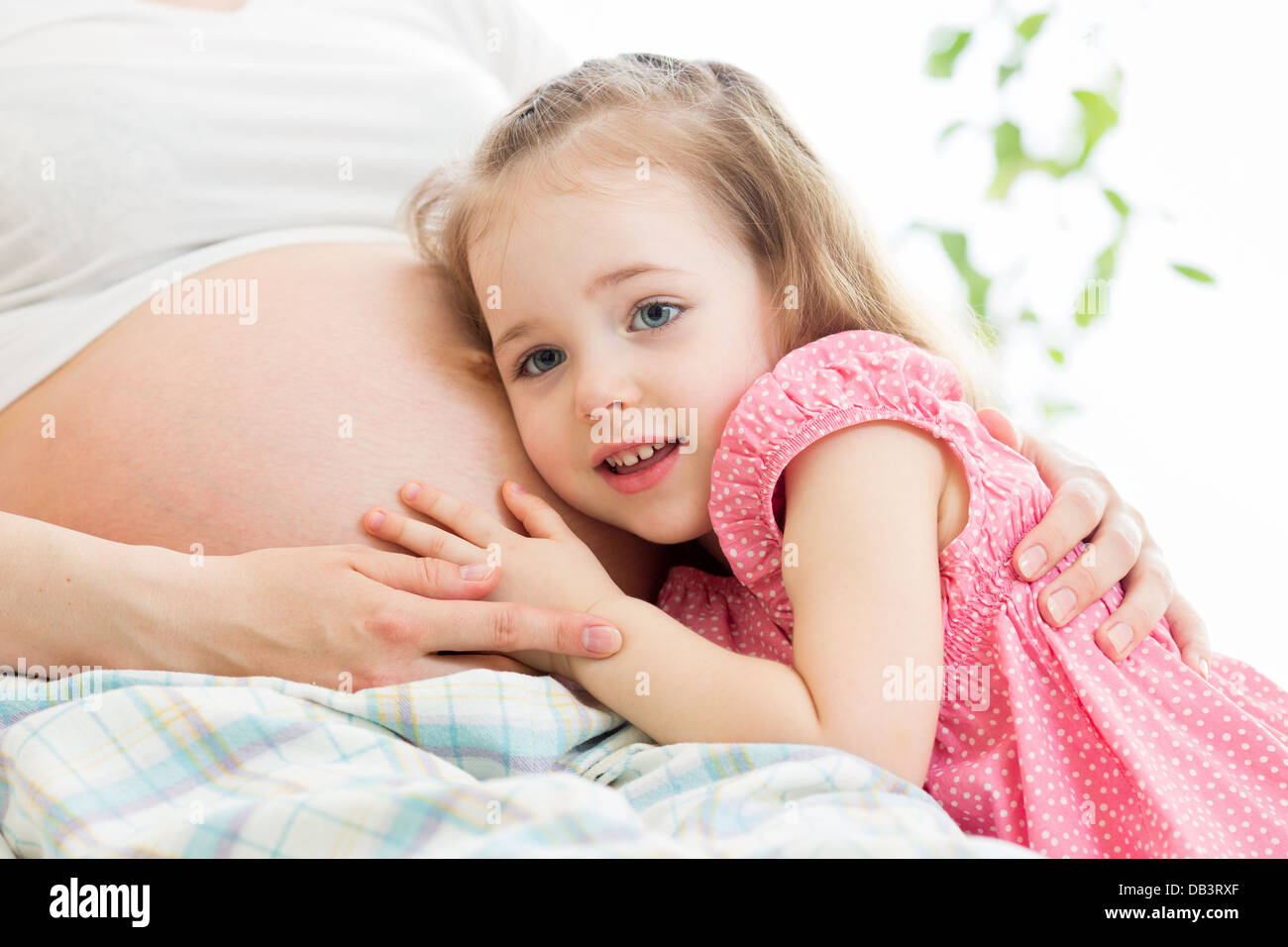 Kind Mädchen hören Bauch der schwangeren Mutter Stockfoto