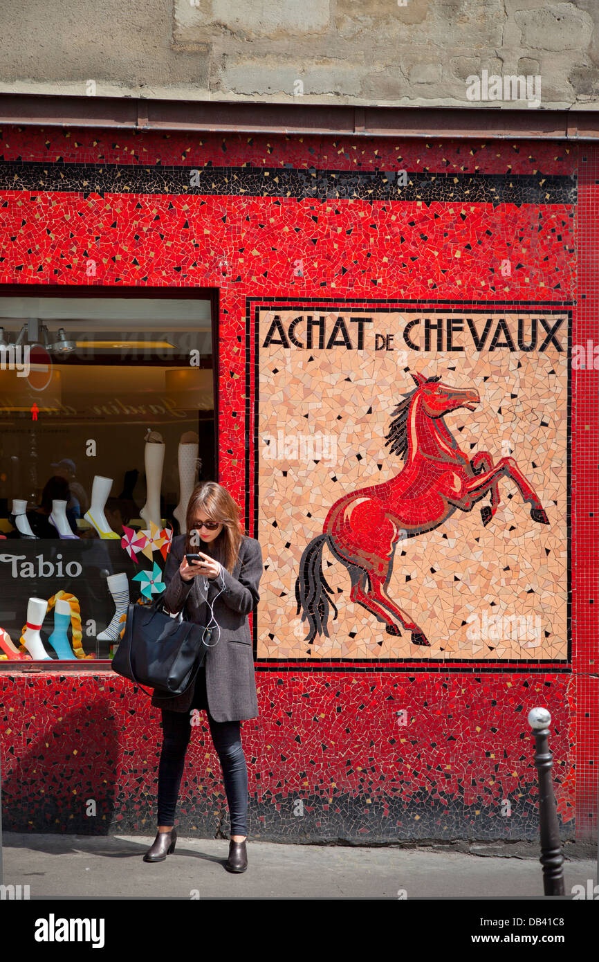 Frau SMS vor historischen Pferd Metzgerei laden, das ist jetzt eine Socke Geschäft, Paris Frankreich Stockfoto