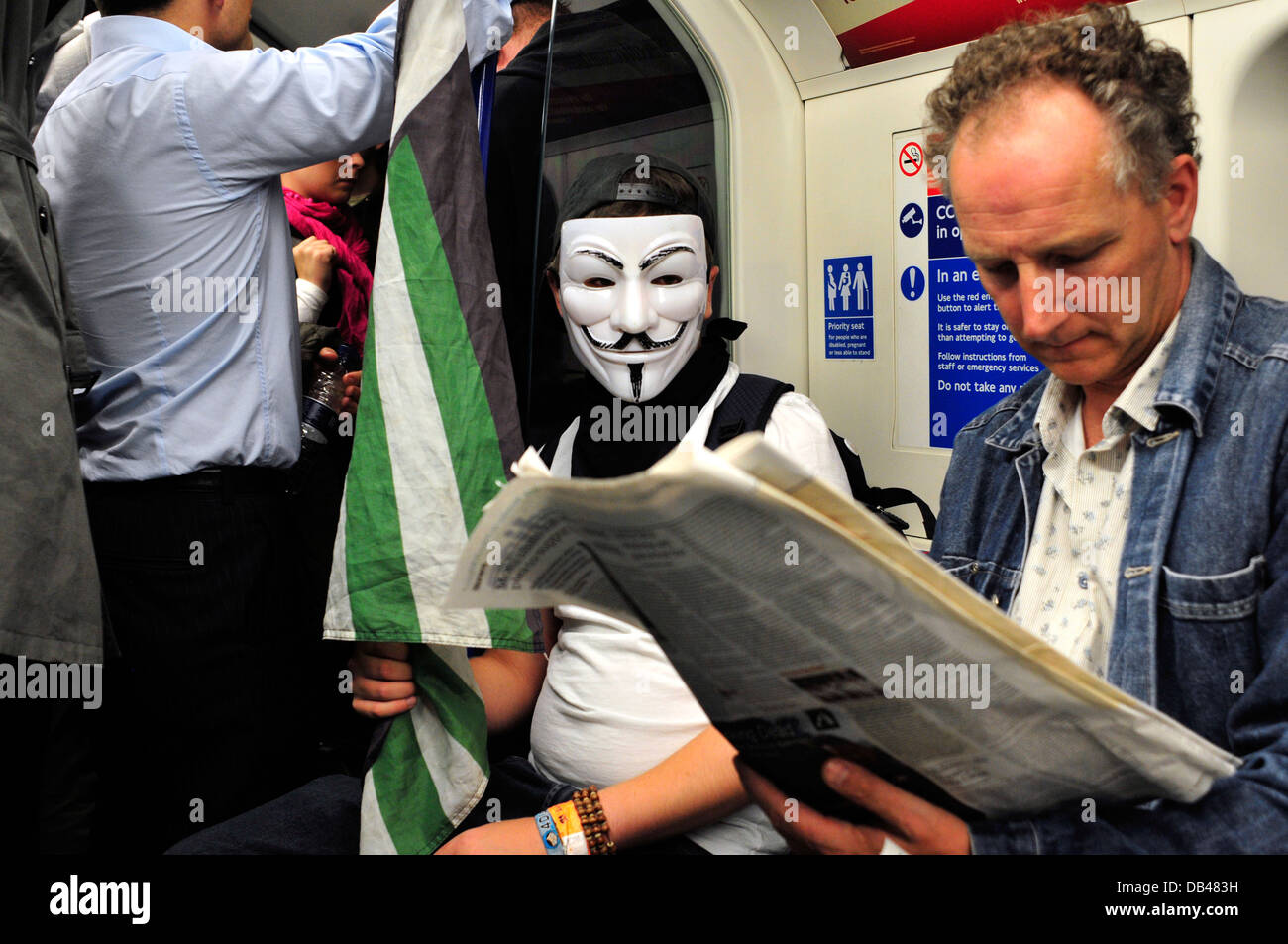 Ein Mann mit einer anonymen Maske in der u-Bahn. London, Vereinigtes Königreich. Stockfoto