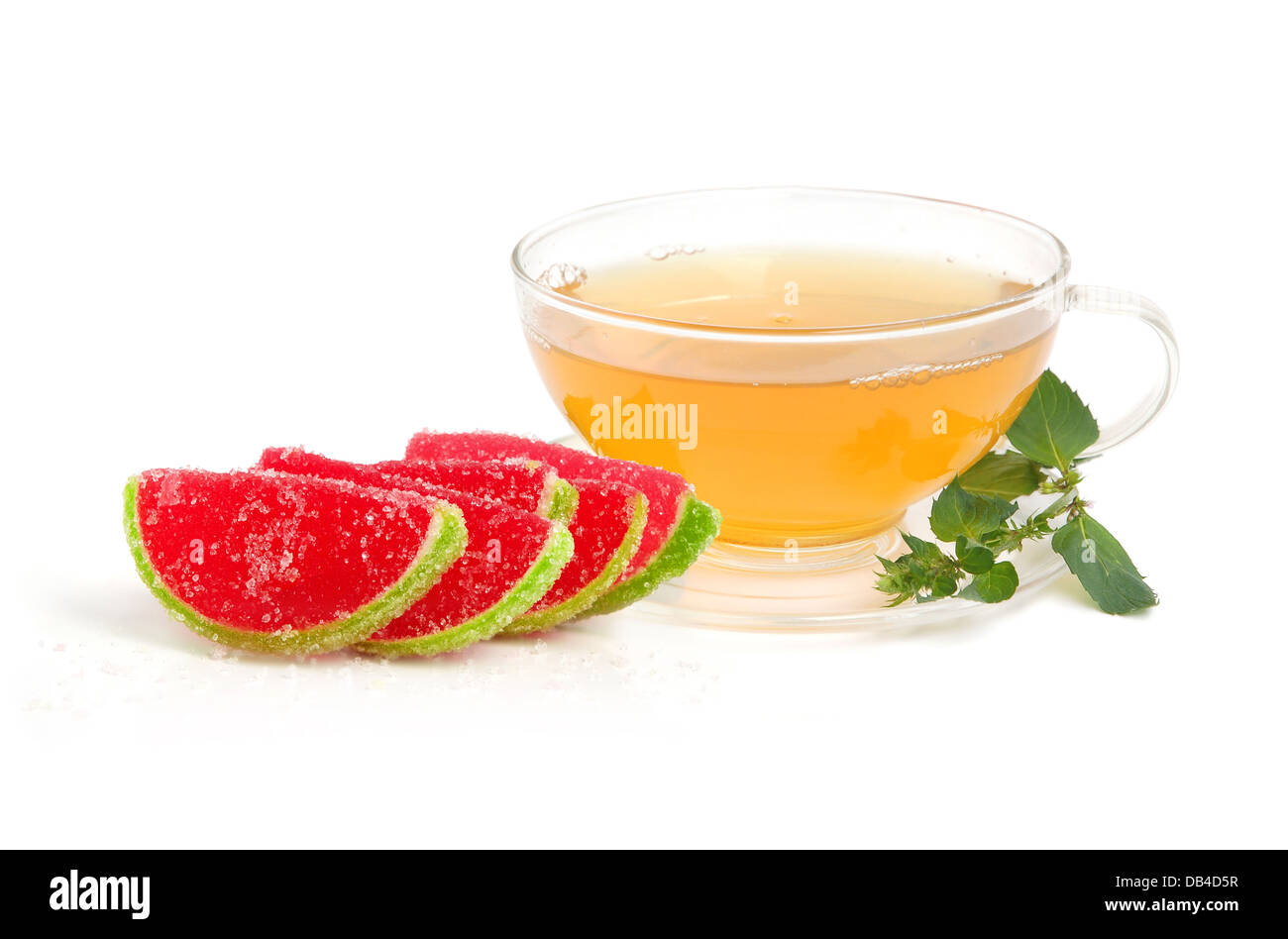 Tasse grüner Tee mit Scheiben von Gummibärchen Wassermelone Süßigkeiten und Minze Blätter auf weißem Hintergrund Stockfoto