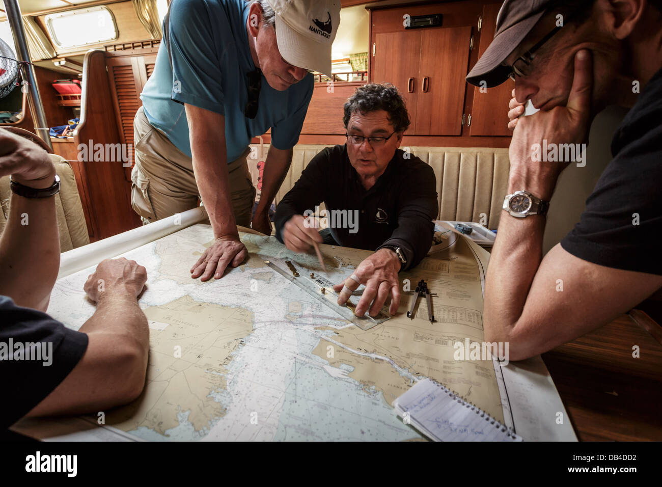 Der Kapitän und die Crew studieren die Navigationskarten, um den Segelkurs zu bestimmen Stockfoto