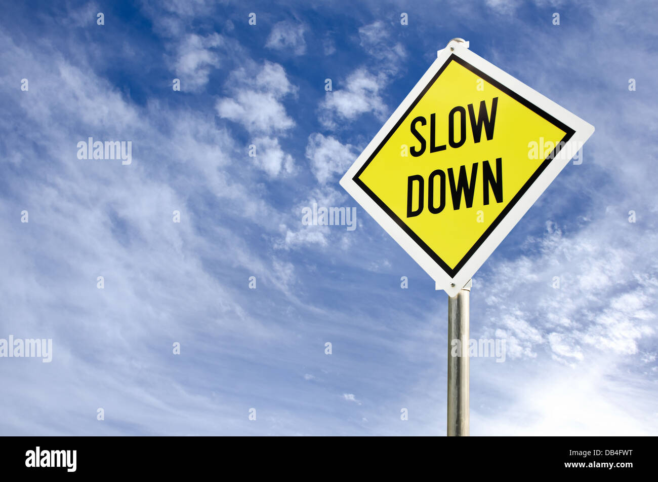 Slow Down gelbe Verkehrszeichen auf blauen Himmel mit Wolken-Hintergrund Stockfoto