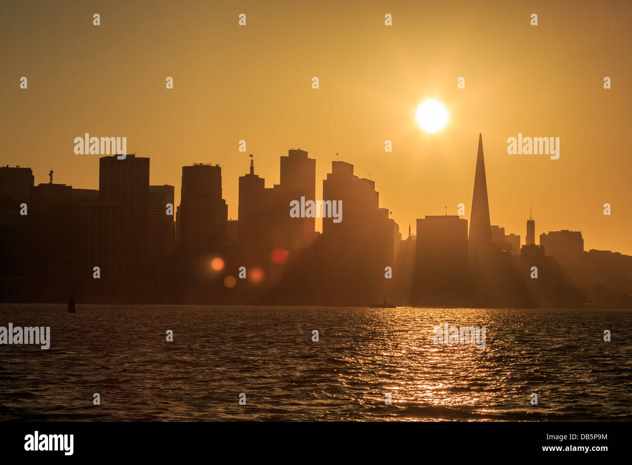 Der Sonnenuntergang hinter der Skyline von San Francisco wirft goldene Schatten Stockfoto