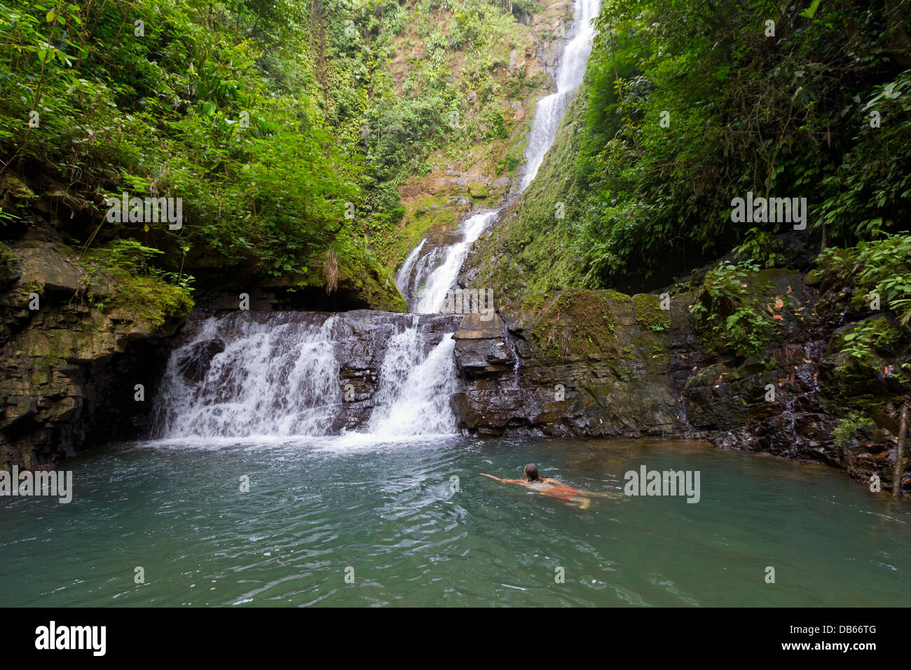 Frau, Schwimmen unter einem Wasserfall in Costa Rica. Stockfoto