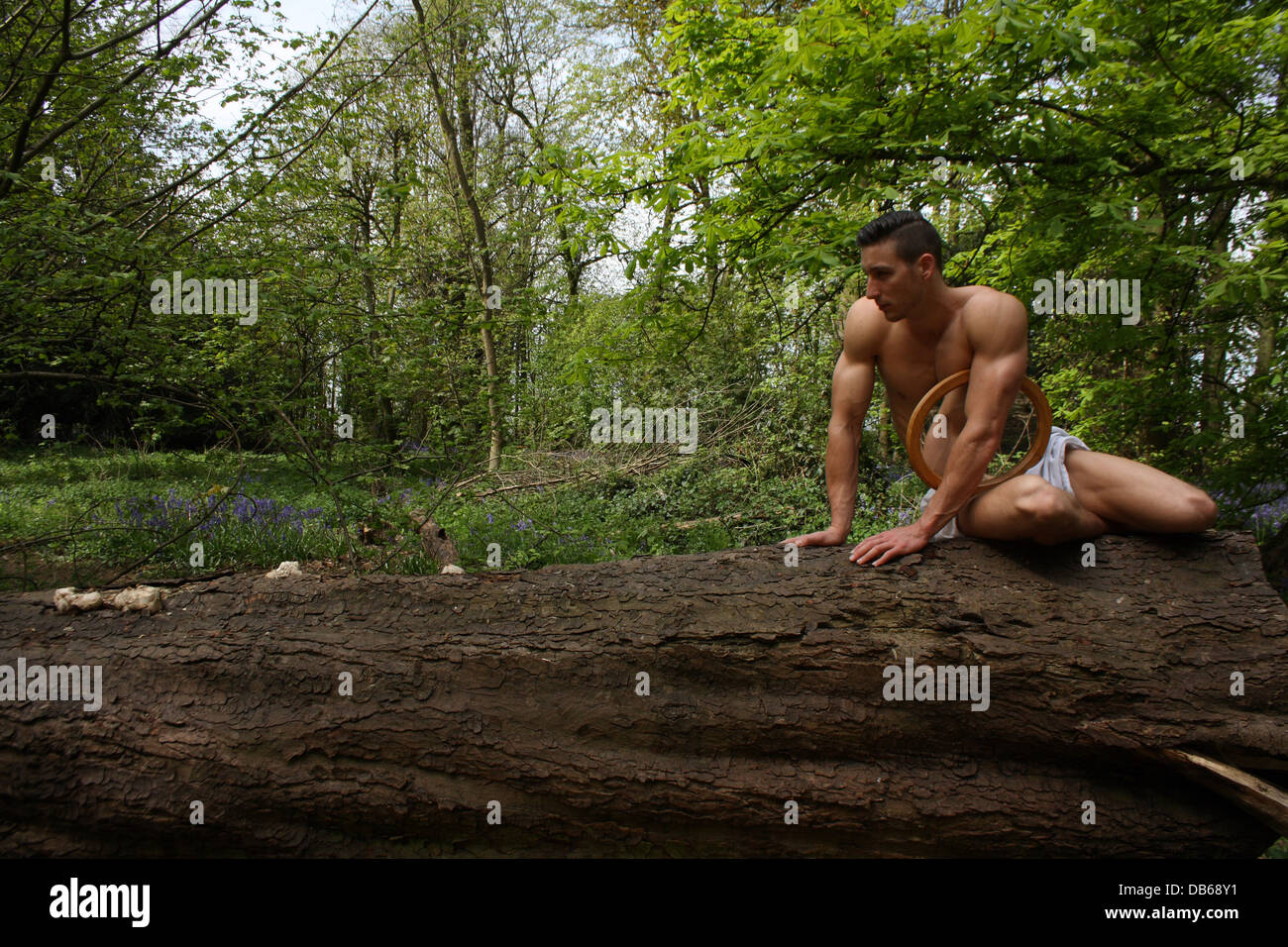 Männliches Modell sitzen auf einem Baumstamm mit einem Spiegel. Stockfoto