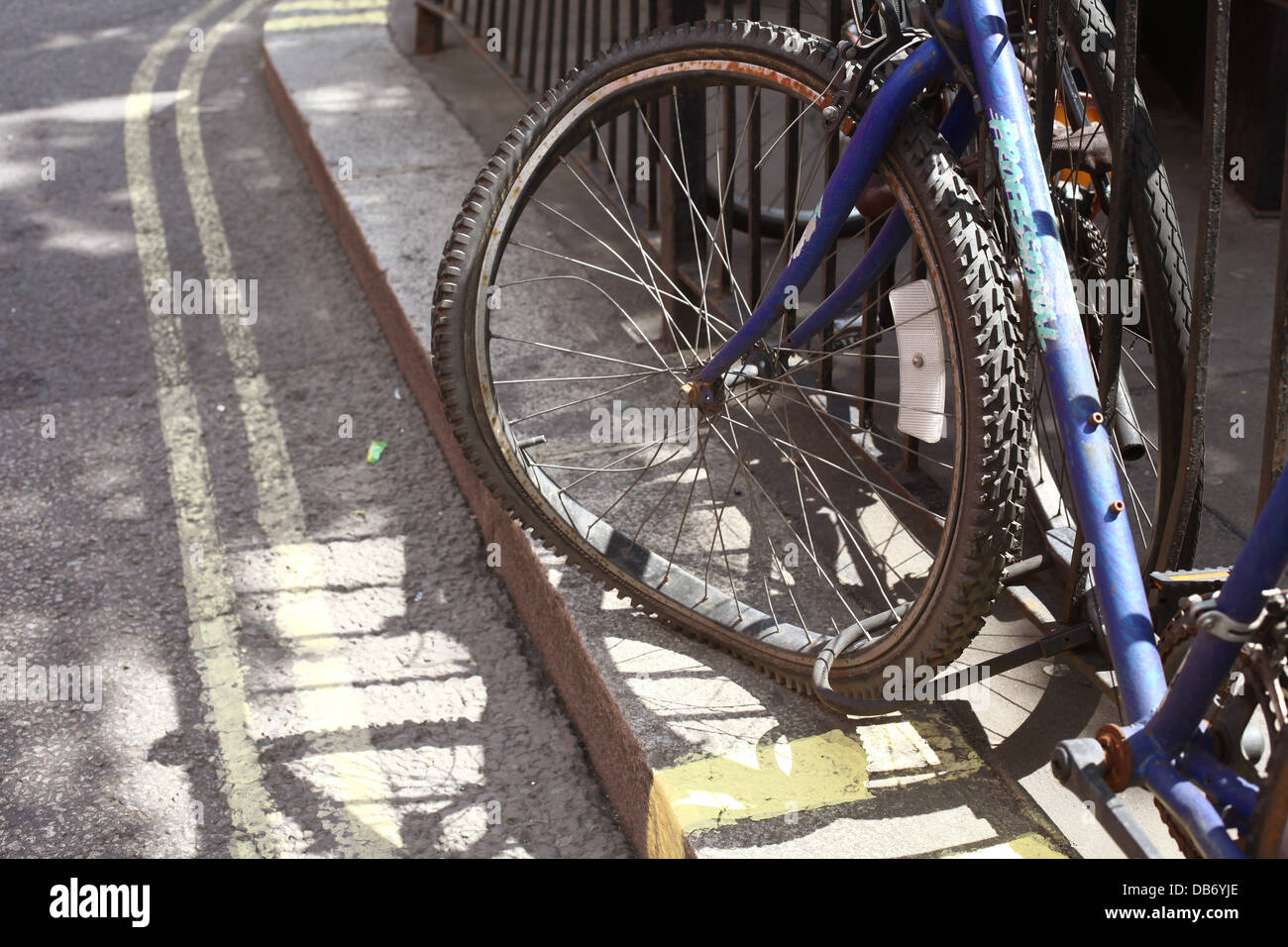Fahrrad-Rad angekettet an ein Geländer im Zentrum von London W2 angeschnallt. Stockfoto