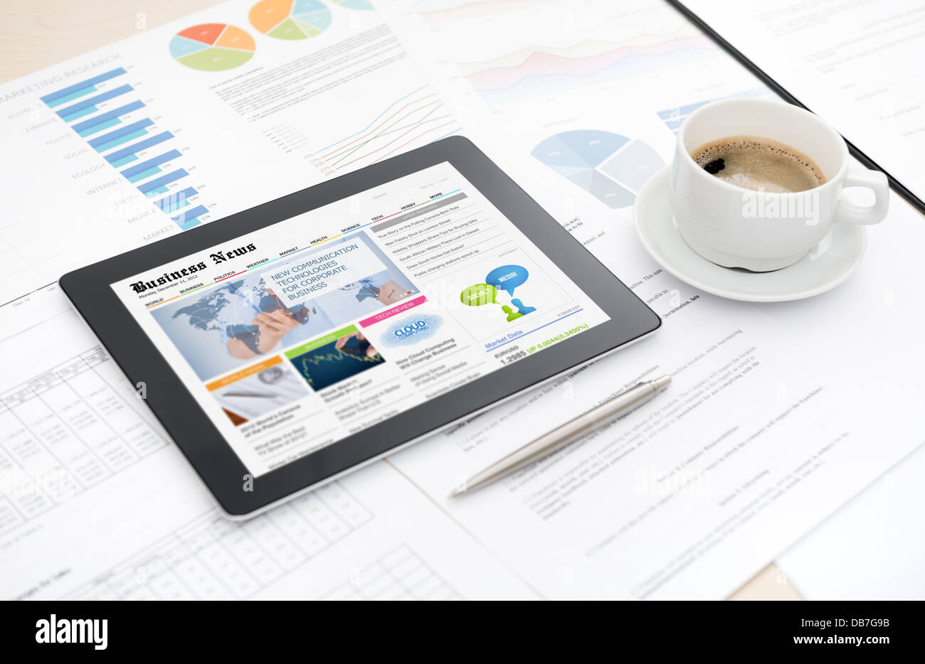 Digital-Tablette mit Business-Medien-Website auf einem Bildschirm liegen auf einem Schreibtisch mit Papiere und Dokumente, Stift und Tasse Kaffee Stockfoto