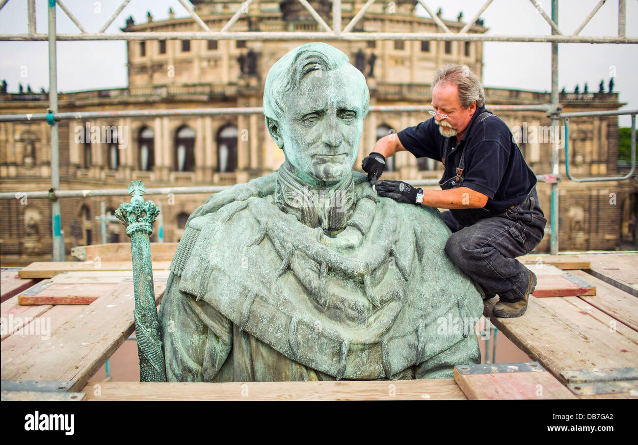 Restaurator Andreas Kunze arbeitet auf das bronzene Reiterstandbild des Königs Johann von Sachsen vor der Semperoper in Dresden, Deutschland, 25. Juli 2013. Für rund 75 000 Euro werden die Oberflächen der Statue vor Schmutz, Staub und Rost Ablagerungen gereinigt. Im Jahre 1889 vom Bildhauer Johannes Schilling geschaffen erinnert das Denkmal König Johann von Sachsen (1801-1873), die den Bau der Semperoper in Auftrag gegeben. Foto: Hannibal Stockfoto