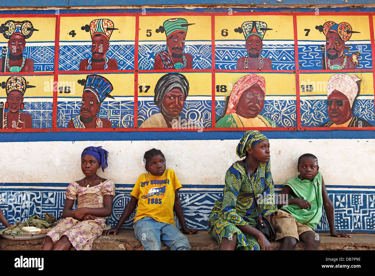 Jungen und Mädchen sitzen vor der Reihe von Vorfahren auf des Sultans-Palast von Foumban Stockfoto