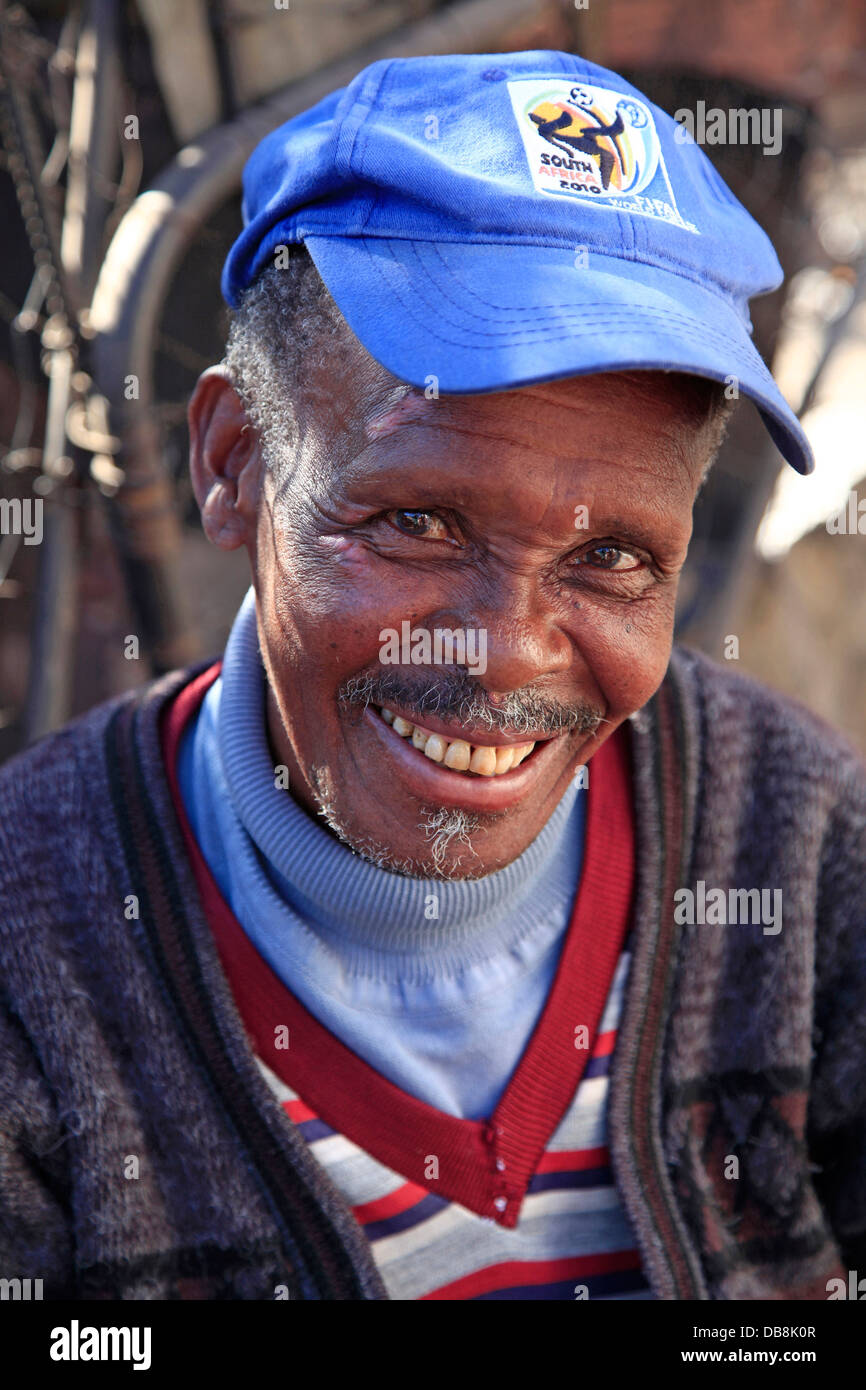 ältere schwarze Mann lächelnd mit einer Mütze aus 2010 World Cup Soccer, in Kliptown Township Soweto, Johannesburg Stockfoto