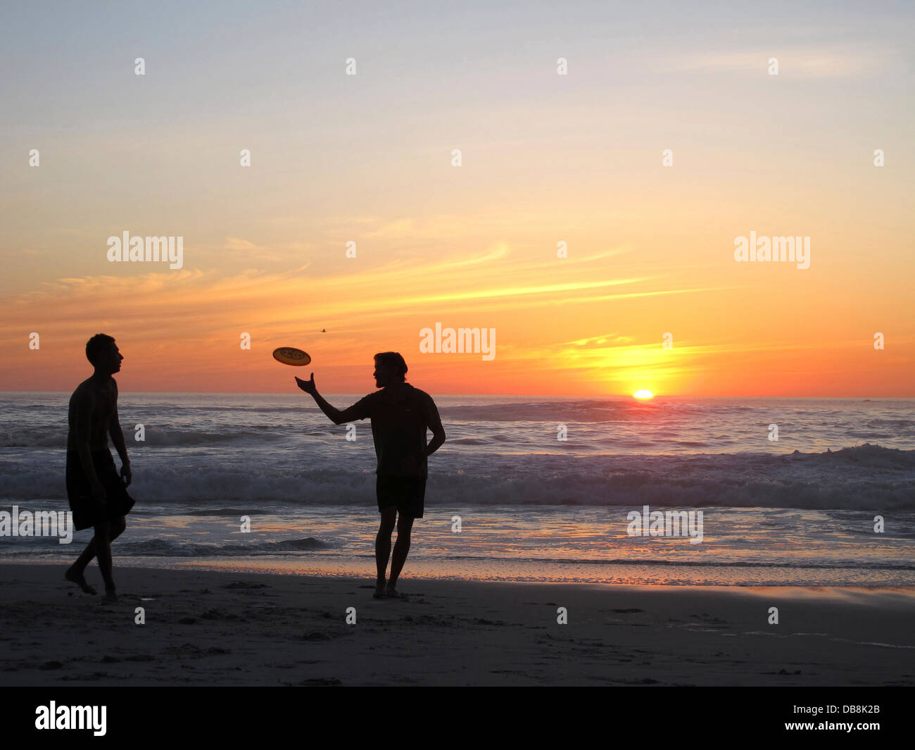 Frisbee-Spieler am Clifton Beach in Kapstadt bei Sonnenuntergang Stockfoto