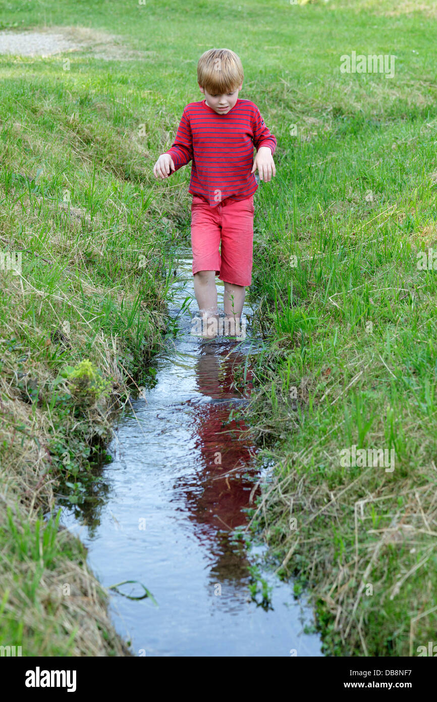 kleiner Junge waten durch einen stream Stockfoto