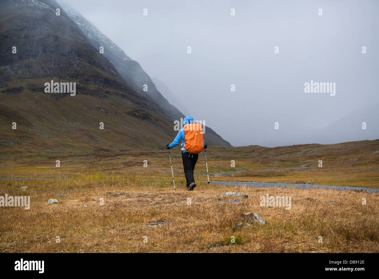 Weibliche Wanderer beobachtet, wie Herbst Schnee Sturm Ansätze in Tjäktjavagge Kungsleden unterwegs, Lappland, Schweden Stockfoto