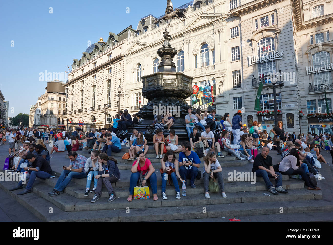 Touristen und Besucher sitzen auf den Stufen des Eros-Statue am Picadilly Circus London England UK Stockfoto