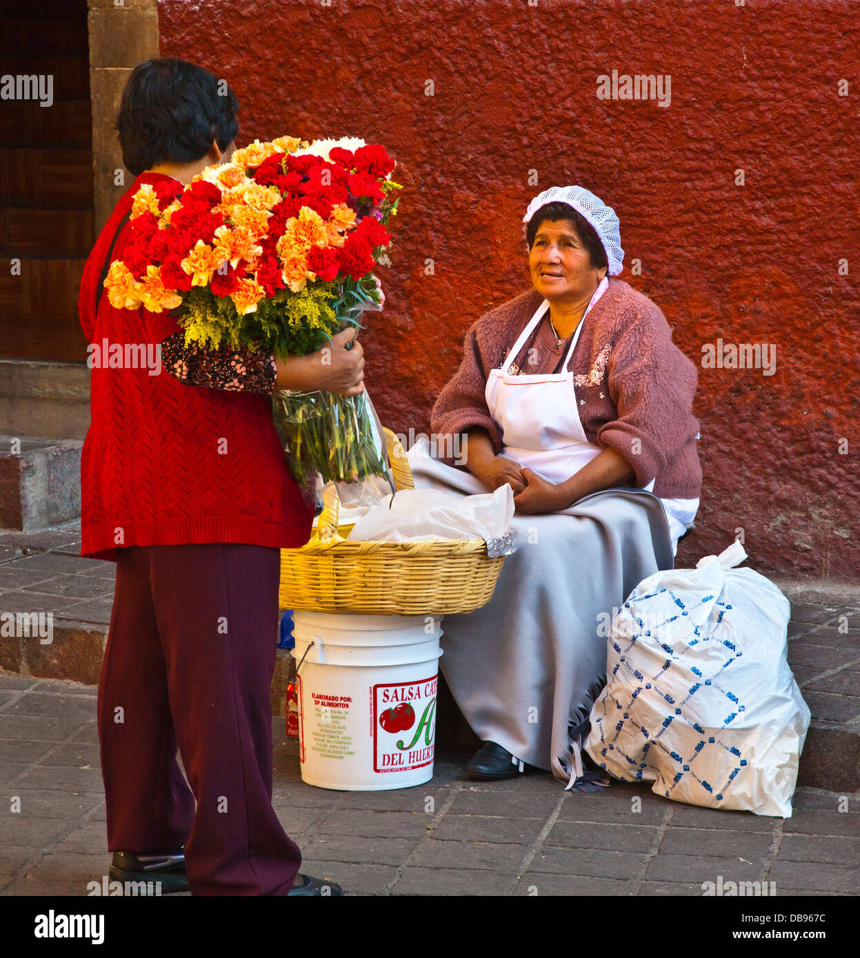 Eine Blume-Hersteller stoppt, um mit einer Frau, Verkauf von Backwaren - GUANAJUATO, Mexiko sprechen Stockfoto