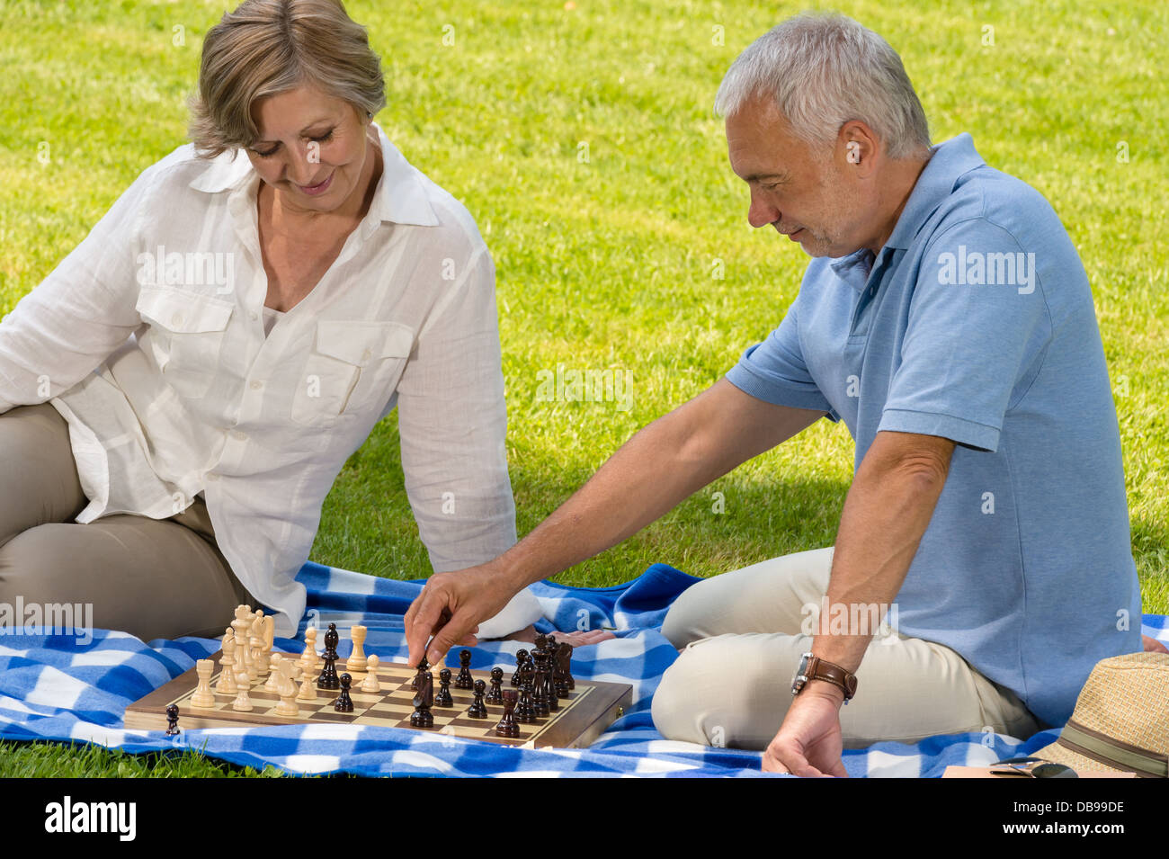 Pensionierte älteres Paar beim Schachspiel im Park sitzen Decke Rasen Stockfoto