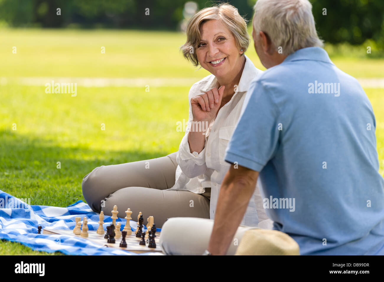 Ältere Frau und Mann spielt Schach auf Decke Sommerpark Stockfoto