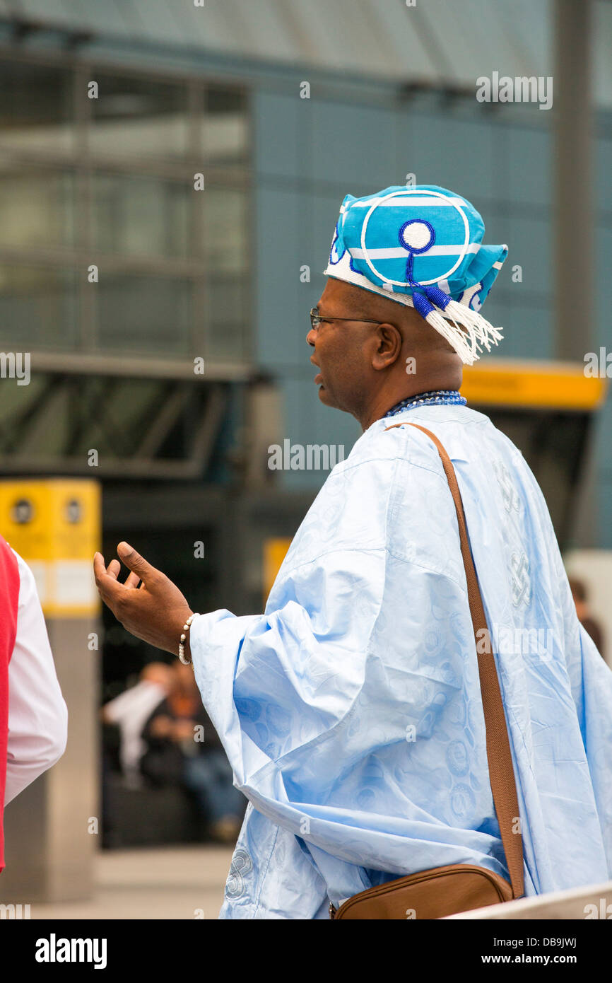 Ein afrikanischer Herr in Reihenstandmotor afrikanischen Kleid am Flughafen Heathrow, London, UK. Stockfoto