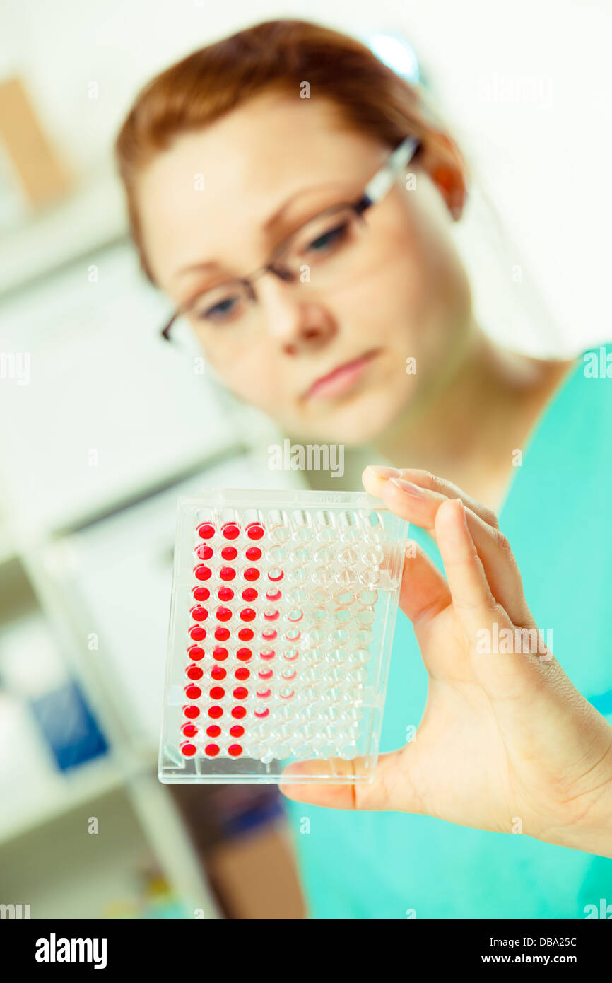 Mädchen hält in einer Hand Multiwell im Labor Stockfoto
