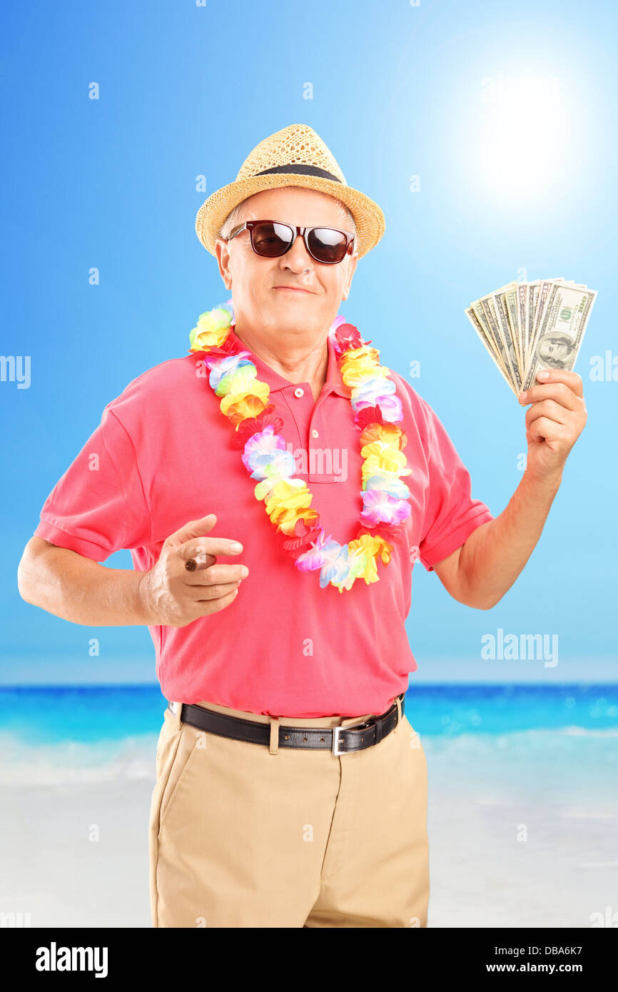 Zufrieden Mann hält eine Zigarre und US-Dollar, an einem Strand Stockfoto