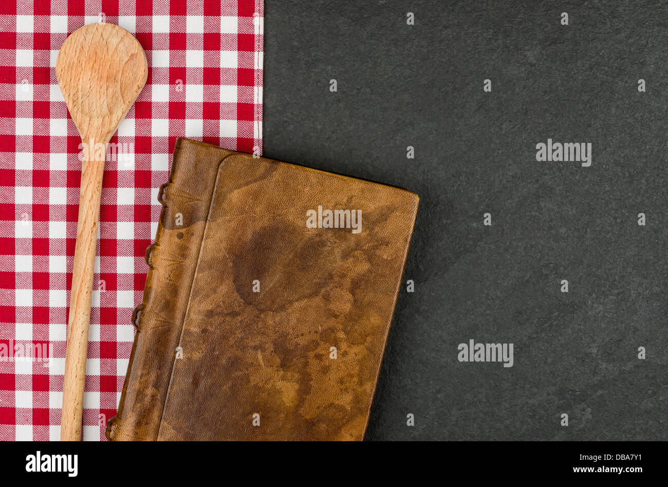 Kochlöffel und Coockbook auf einer Schiefertafel Platte Stockfoto