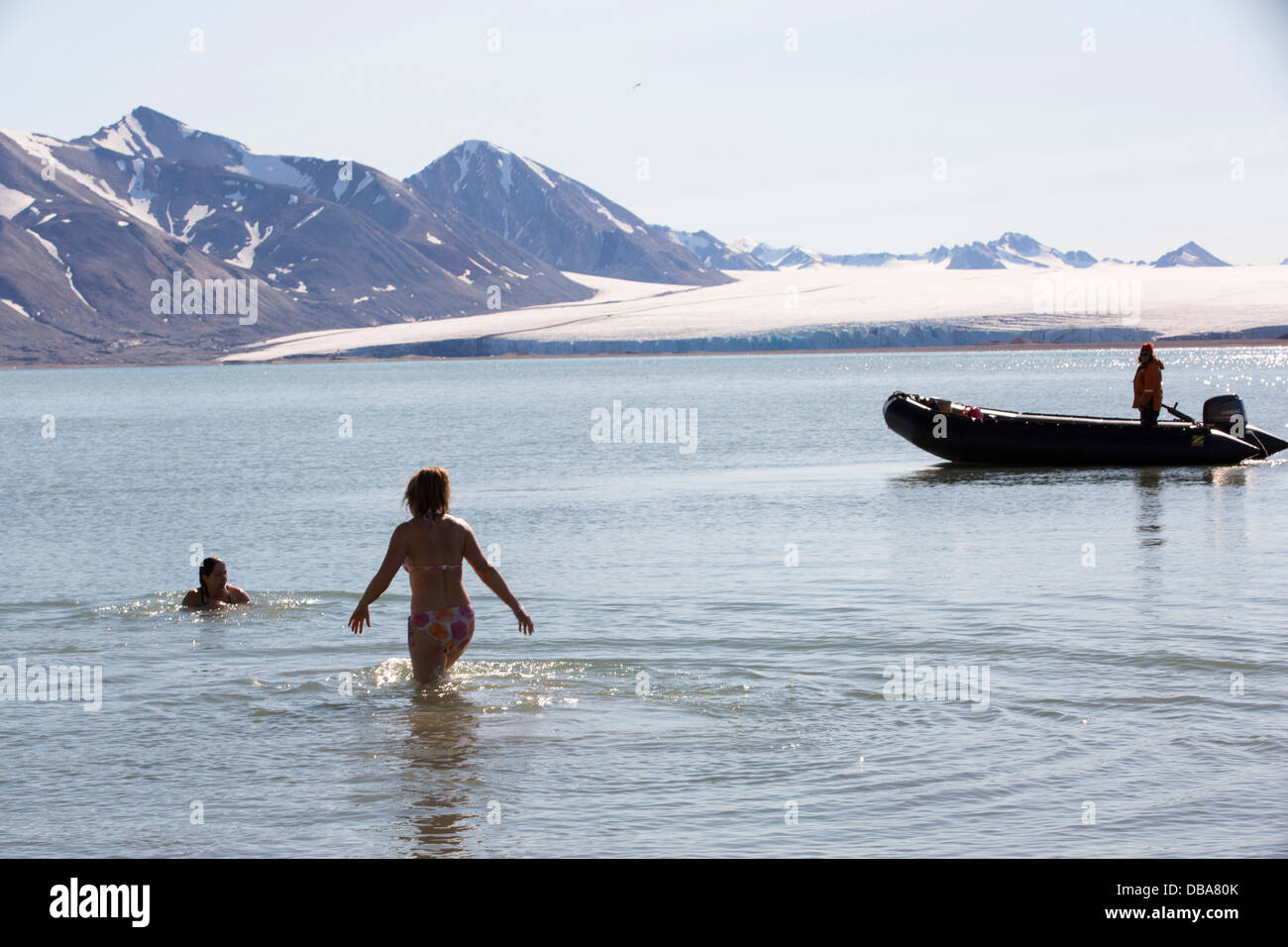 Frau zu nehmen ein erfrischendes Bad im arktischen Ozean im Norden Svalbard vor einem Gletscher. Stockfoto