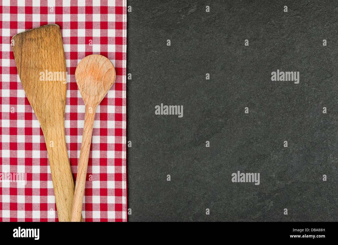 Holzlöffel auf dem Schiefer Teller mit einem rot karierten Tischdecke Stockfoto