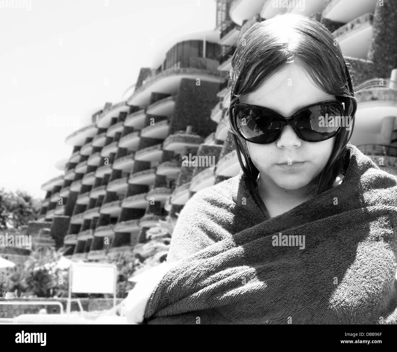 pre-teen Mädchen, große Sonnenbrille, die auf der Suche nach unten. nasses Haar. Handtuch um die Schultern gewickelt. Schwarz und weiß. Filmstar-Altbau Stockfoto