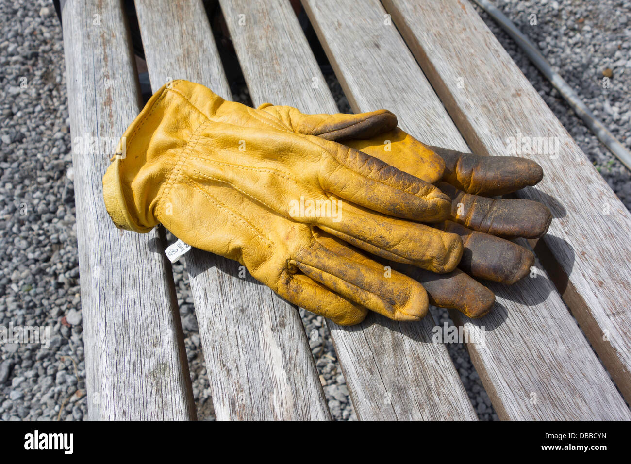 Ein paar Gartenhandschuhe gelb Leder auf einer Bank Stockfoto